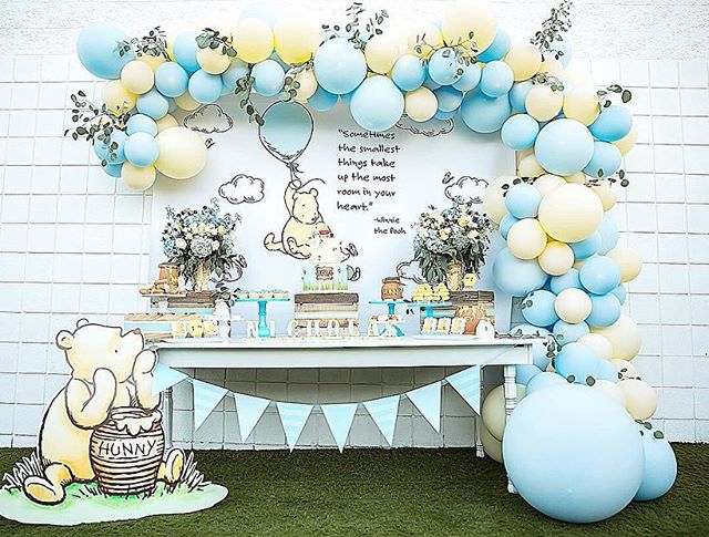 Winnie the pooh baby shower theme with yellow and blue balloons, desserts, flowers, and decorations.