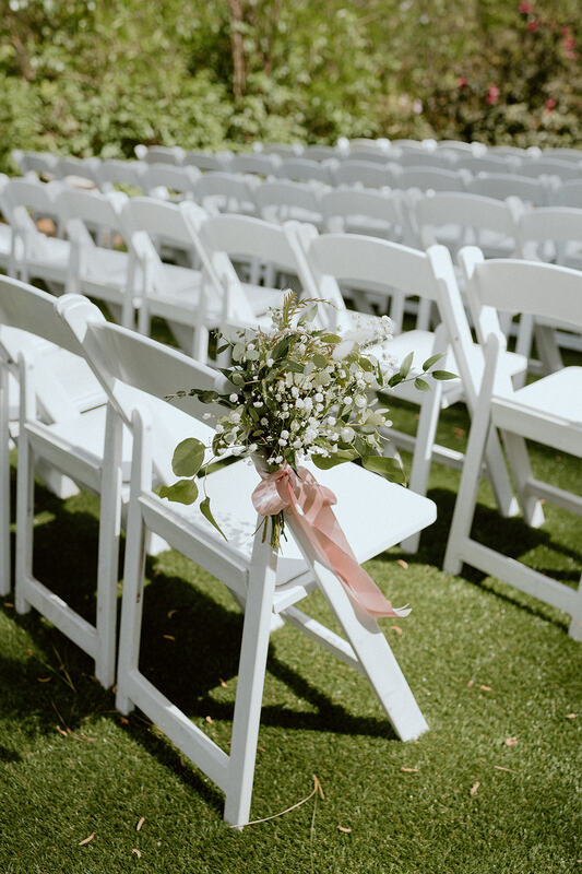 floral arrangement on white ceremony chairs