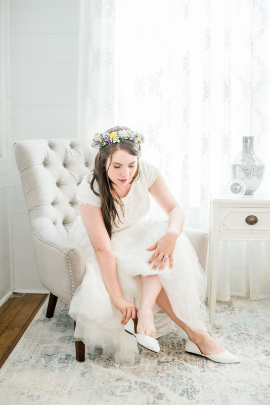 bride with spring flower crown putting on wedding shoes