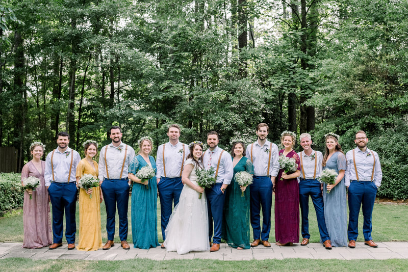 wedding party with groomsmen in suspenders and bridesmaids in bright lace dresses