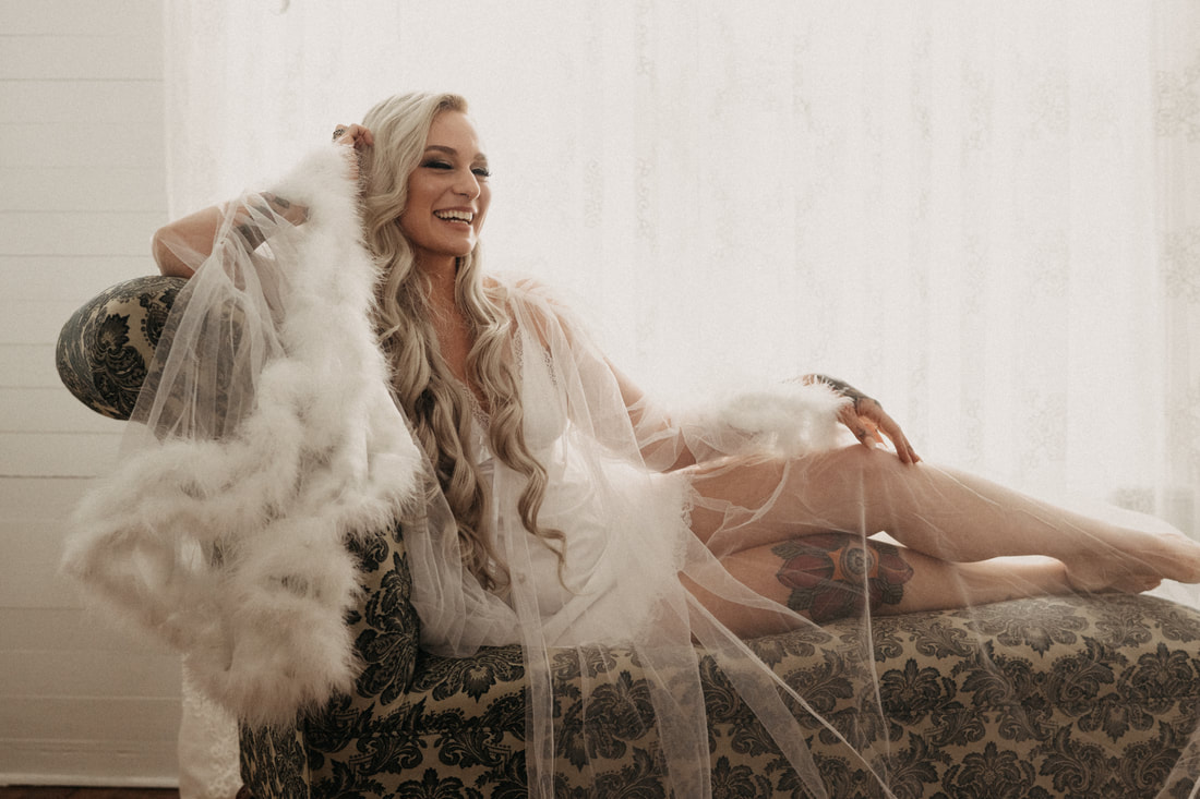bride in feathered robe sitting on chaise lounge