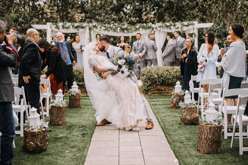 groom dipping bride for kiss at outdoor garden wedding ceremony